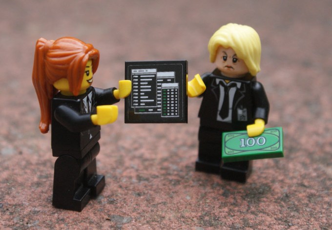 Lego characters hold a report and money to pay the report cost
