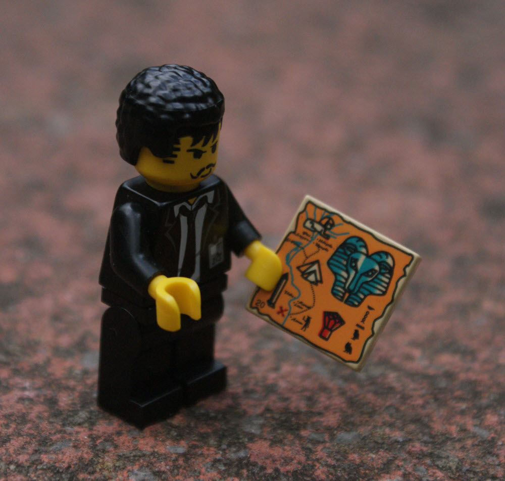 Lego character looking at a tile with hieroglyphs on it